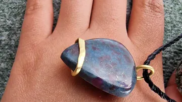 Hand trägt blauen Edelstein-Anhänger.