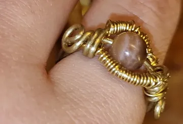 Hand trägt einen goldenen Draht-Ring.