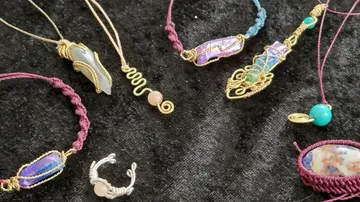 Handmade pendants and rings on dark fabric surface.