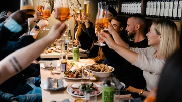 People toasting glasses at a restaurant gathering.