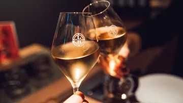 Two glasses clinking in dim setting.