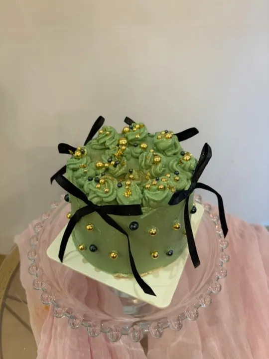 Grüner Kuchen mit Perlen auf Glasständer.