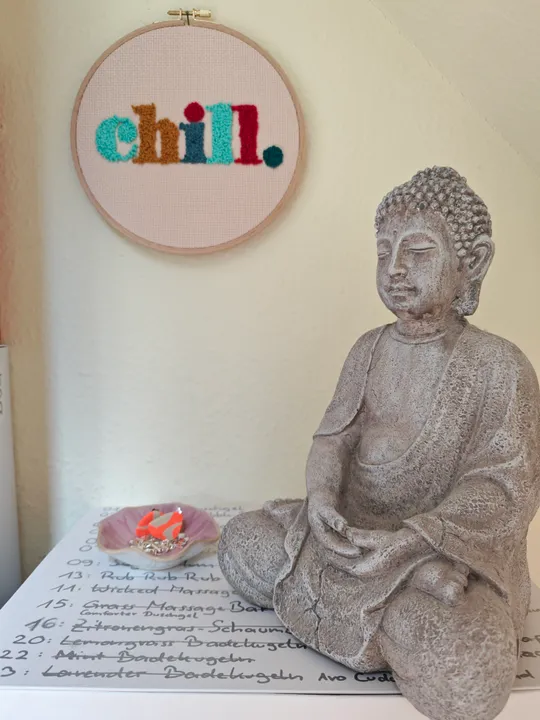 Buddha-Statue neben Stickerei und Notizen.