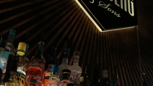 Liquor bottles stacked, bar sign above.