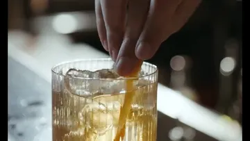 Hand stirring iced drink with garnish.