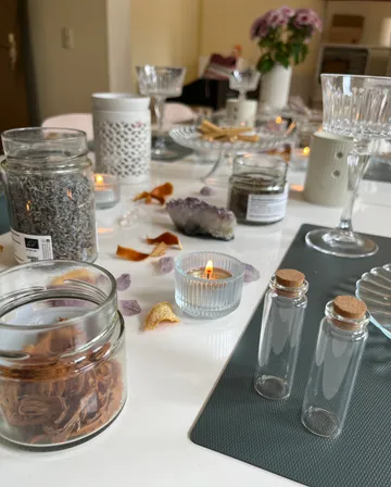 Glasgefäße, Kerzen und Blumen auf einem Tisch.