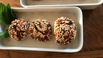 Sesambedeckte Falafel mit Minze auf Tellern.