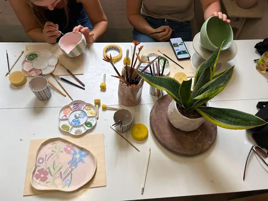 Menschen bemalen Keramik an einem Tisch.