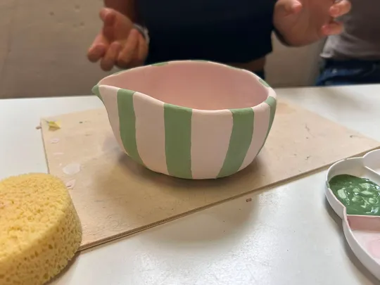 Gestreifte Schale wird an einem Tisch bemalt.