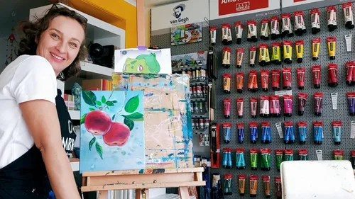Woman smiling, standing by painted canvas, art store.