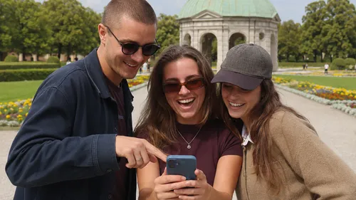 Drei Freunde lachen über ein Handy draußen.
