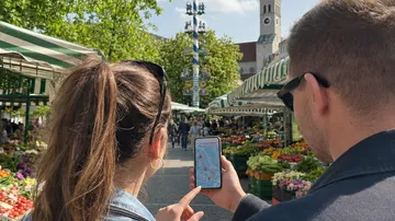 Two people navigate market with phone.
