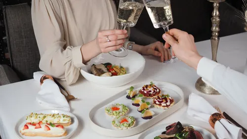 Two people toast with champagne, dining table.