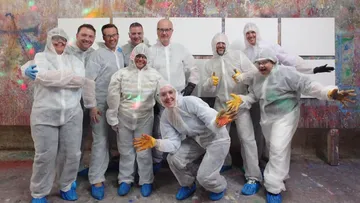 Personen in Schutzanzügen posieren in bemaltem Raum.