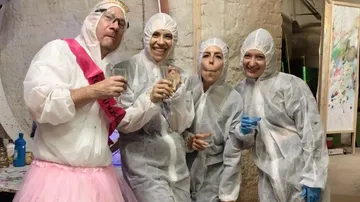 Four people in coveralls posing indoors.