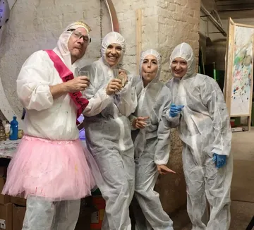 Four people in protective suits celebrating indoors.