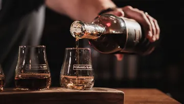 Person pouring whiskey into a glass.