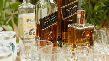 Liquor bottles with glasses on wooden table.