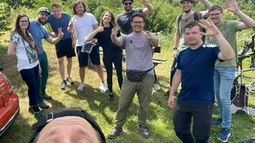 Gruppe von Menschen posiert draußen, lächelnd.