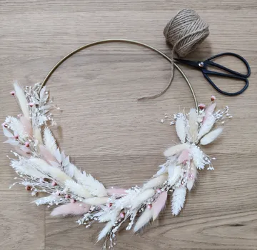 Dekorativer Kranz mit Blumen auf Holztisch.