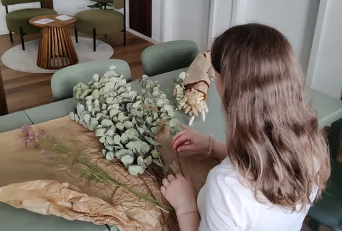 Frau arrangiert Blumen auf einem Tisch innen.