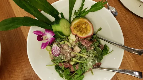 Salat mit Steak, Gurke, Passionsfrucht, Holztisch.