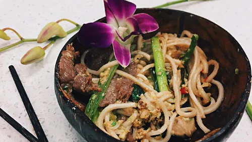 Noodles with meat and flowers in a bowl.
