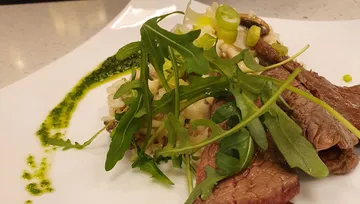 Steak mit Rucola auf weißem Teller.