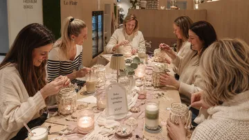 Frauen basteln an einem Tisch mit Kerzen.