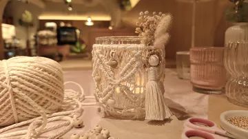 Makramee-Kerzenhalter auf Tisch mit Garn.