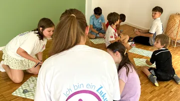 Kinder sitzen auf dem Boden, basteln.