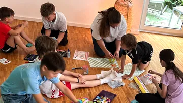 Children crafting on wooden floor indoors.