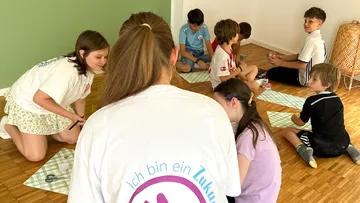 Kinder sitzen auf Boden, basteln.