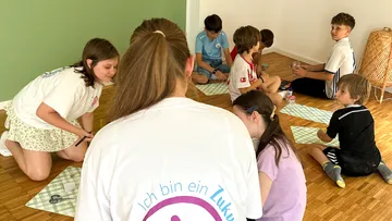 Kinder sitzen auf dem Boden im Klassenzimmer.