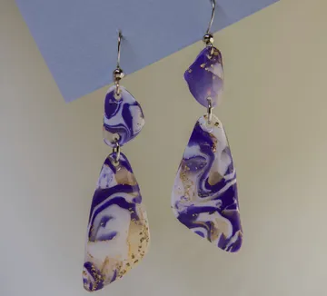Abstract earrings hanging against a plain background.