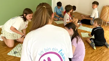 Kinder sitzen in einem Klassenzimmer und basteln.