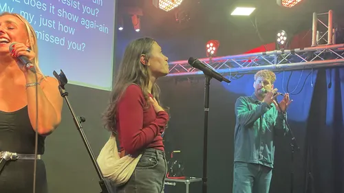 Menschen singen und spielen auf Bühne.