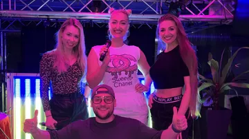 Four people posing on stage with lights.