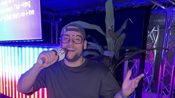 Man singing karaoke, colorful stage lighting.