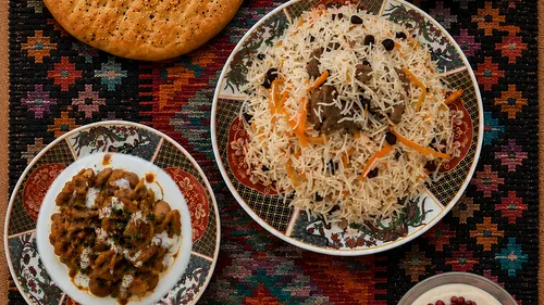 Rice, meat, bread, and stew on patterned cloth.