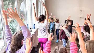 Lehrerin leitet Kinder im Yoga-Unterricht.