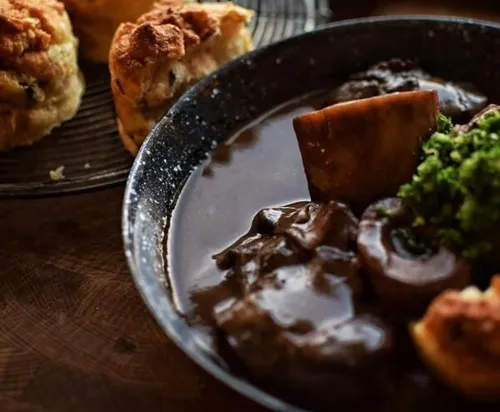 Oxtail stew with broccoli, scones nearby.