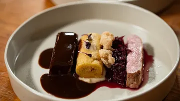 Gourmetgericht mit Fleisch und Soße auf Teller.
