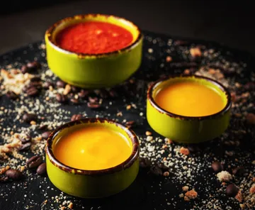 Three bowls with sauces on black surface.