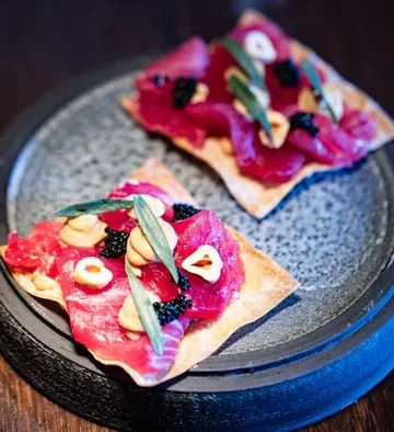 Gourmet crackers with toppings on a plate.