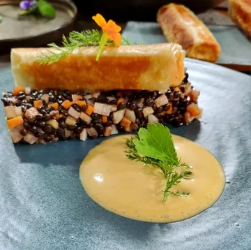 Gourmetgericht mit Linsen und Sauce.