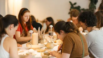 People crafting at a table with candles.