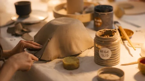 Hands shaping clay in a pottery workshop.