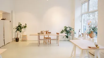 Minimalist room with wooden tables, plants, white walls.