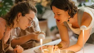 Two women crafting pottery together at a table.